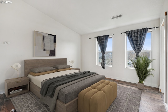 bedroom with lofted ceiling, wood finished floors, visible vents, and multiple windows
