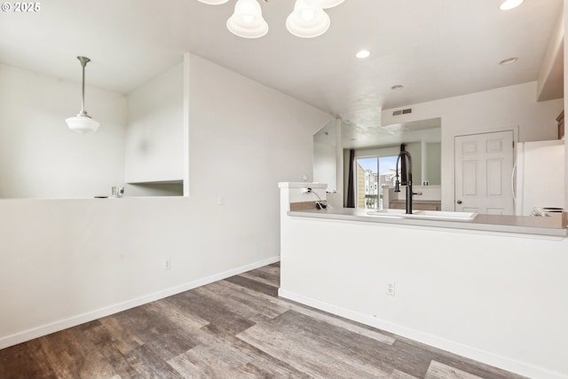 interior space with wood finished floors, baseboards, recessed lighting, freestanding refrigerator, and a sink