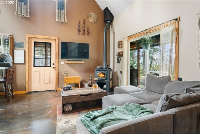 823 Terrace Dr, Scotts Mills, OR 97375 - living area featuring baseboards, a wood stove, finished concrete flooring, and high vaulted ceiling