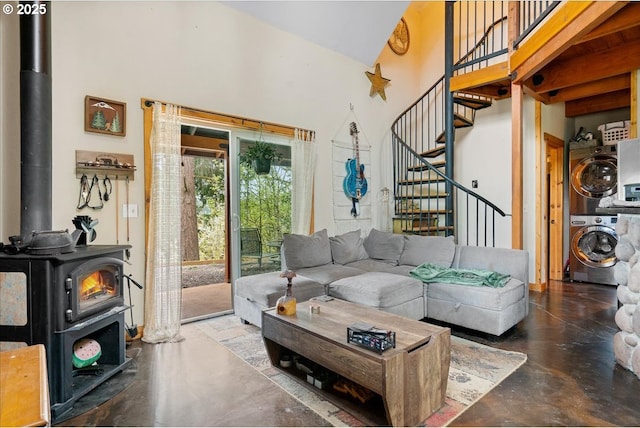 823 Terrace Dr, Scotts Mills, OR 97375 - living area featuring a high ceiling, concrete floors, stairs, stacked washer / drying machine, and a wood stove
