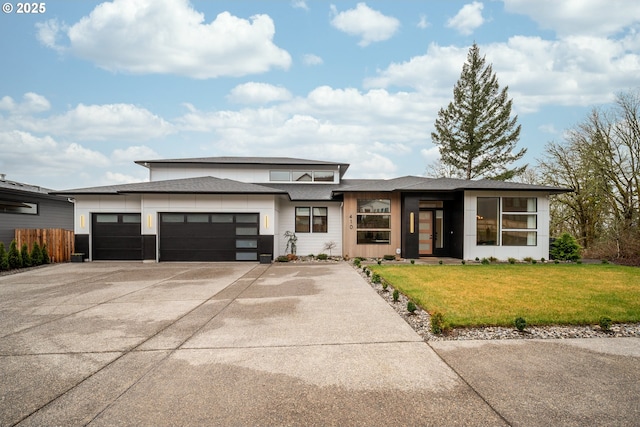 prairie-style home featuring a front yard, fence, driveway, roof with shingles, and an attached garage