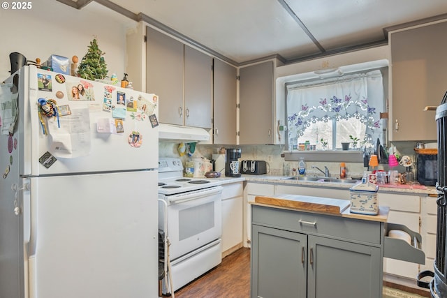 kitchen with tasteful backsplash, sink, gray cabinetry, dark wood-type flooring, and white appliances