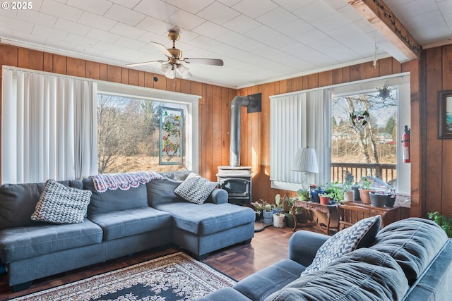 living room featuring plenty of natural light, a wood stove, and wood walls