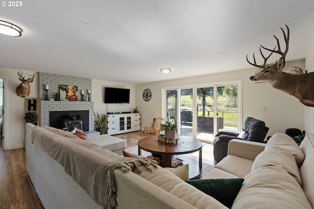 living area with baseboards, a brick fireplace, and wood finished floors