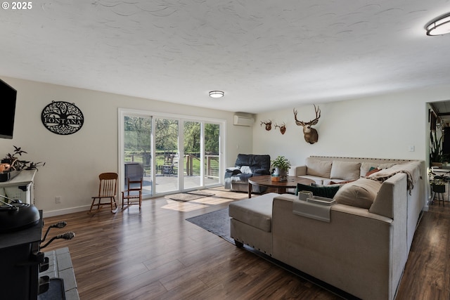 living area with baseboards, a wall mounted AC, and dark wood-style floors