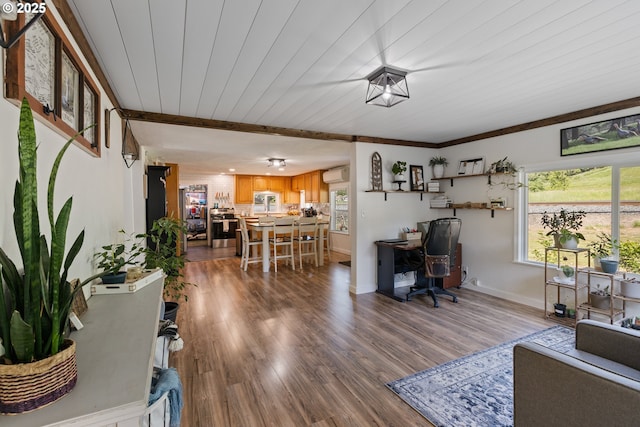 living area with an AC wall unit, baseboards, wood finished floors, and wood ceiling