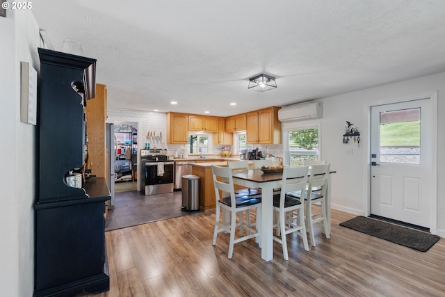 dining space with recessed lighting, baseboards, a wall mounted AC, and wood finished floors