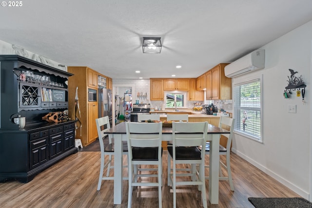 dining space with an AC wall unit, baseboards, recessed lighting, and light wood-type flooring