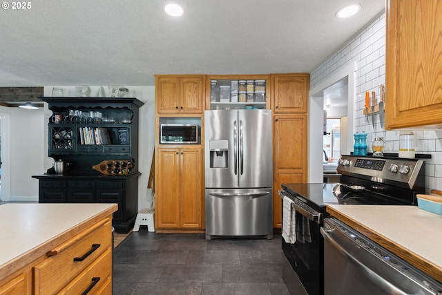kitchen with light countertops, appliances with stainless steel finishes, tasteful backsplash, and glass insert cabinets