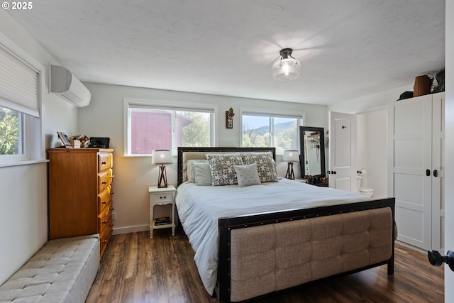 bedroom featuring baseboards, a wall mounted air conditioner, and wood finished floors