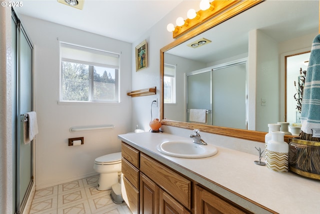 bathroom featuring a stall shower, vanity, tile patterned floors, baseboards, and toilet