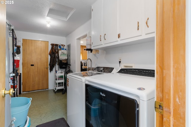 laundry room featuring tile patterned floors, cabinet space, washing machine and dryer, and attic access