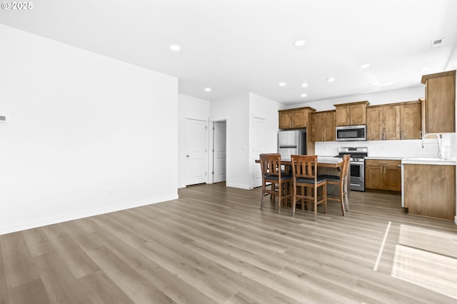 2095 S Heather St, Cornelius, OR 97113 - kitchen with appliances with stainless steel finishes, a kitchen island, recessed lighting, brown cabinets, and light wood finished floors
