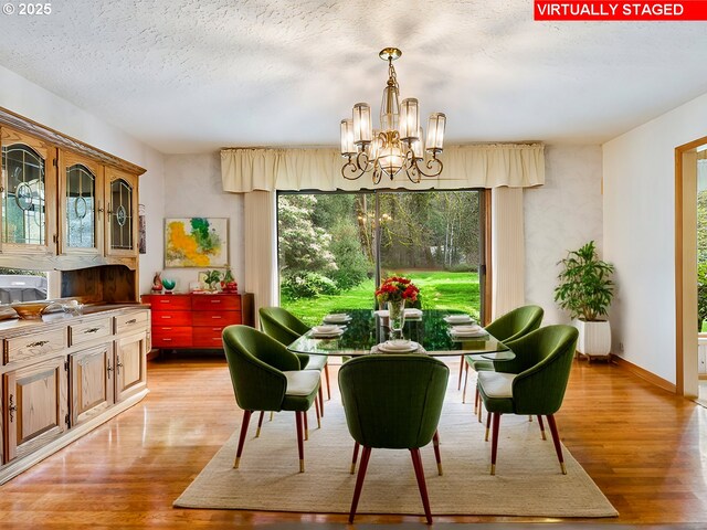 dining area featuring baseboards, a textured ceiling, a notable chandelier, and light wood finished floors