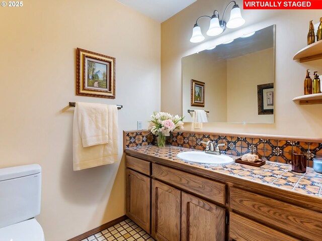 bathroom with toilet, vanity, and baseboards