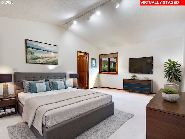 bedroom with light colored carpet, lofted ceiling, and a textured ceiling