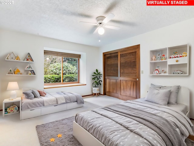 carpeted bedroom featuring a ceiling fan, a closet, and a textured ceiling