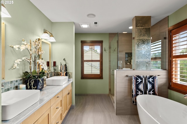 bathroom featuring a shower stall, a freestanding bath, double vanity, and baseboards