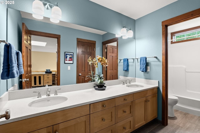 full bathroom with double vanity, toilet, and wood finished floors