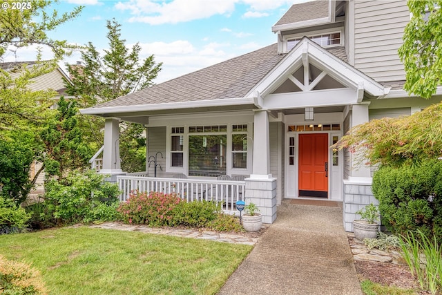 view of front of home with a shingled roof, a porch, and a front yard