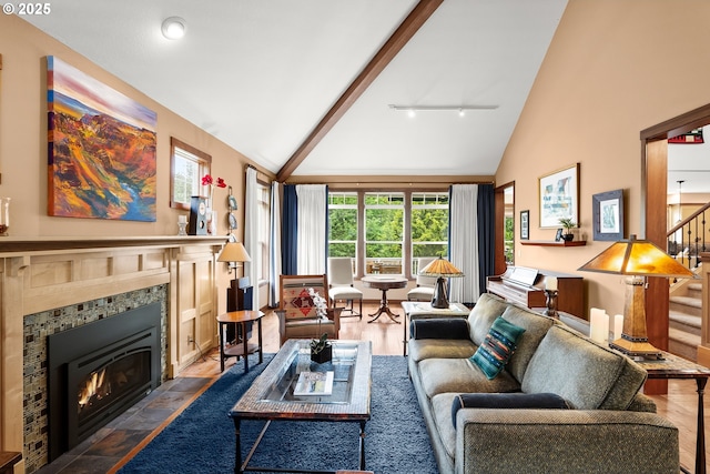 living area featuring a tiled fireplace, high vaulted ceiling, stairway, and wood finished floors