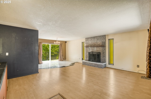 14173 NW Grandview Pl, Banks, OR 97106 - unfurnished living room featuring wood finished floors, a textured ceiling, a chandelier, a fireplace, and baseboards