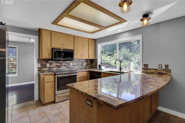 1168 Risden Pl, Eugene, OR 97404 - kitchen featuring appliances with stainless steel finishes, a peninsula, backsplash, dark stone countertops, and light tile patterned floors