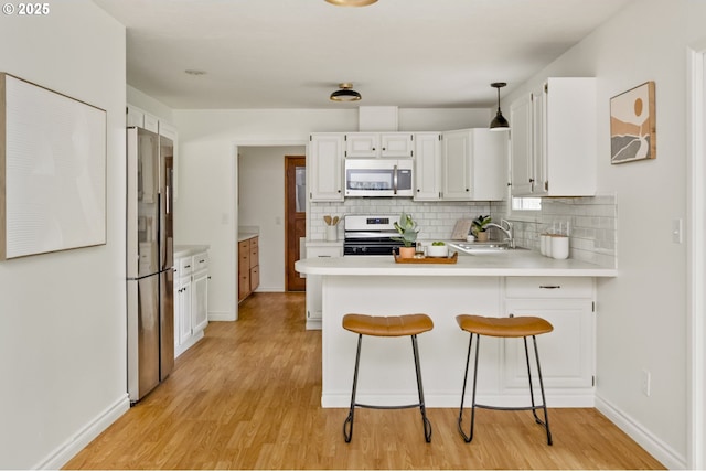 1070 SW Portola Ave, Portland, OR 97225 - kitchen featuring stainless steel appliances, a peninsula, light countertops, backsplash, and light wood finished floors