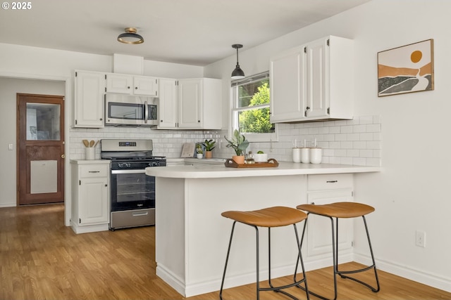 1070 SW Portola Ave, Portland, OR 97225 - kitchen with appliances with stainless steel finishes, light countertops, a peninsula, and tasteful backsplash