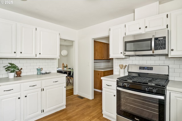 1070 SW Portola Ave, Portland, OR 97225 - kitchen with appliances with stainless steel finishes, light countertops, light wood finished floors, and white cabinetry