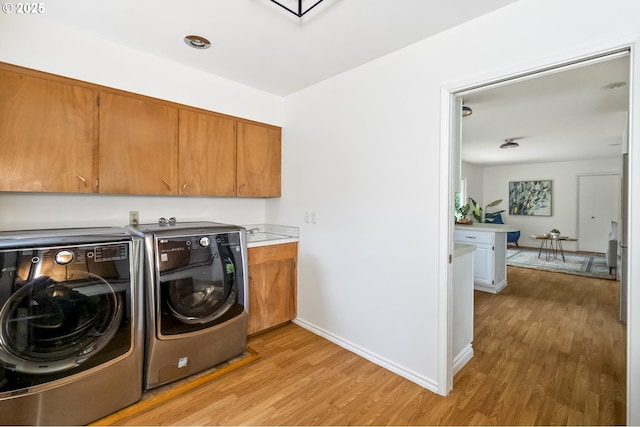 1070 SW Portola Ave, Portland, OR 97225 - laundry area with cabinet space, washing machine and clothes dryer, and light wood-style floors