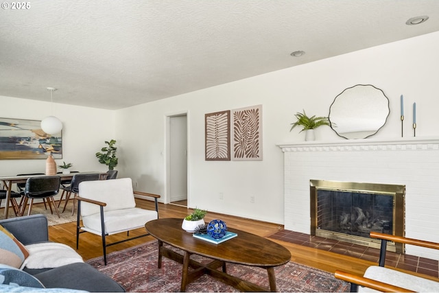 1070 SW Portola Ave, Portland, OR 97225 - living room with wood finished floors, a brick fireplace, and a textured ceiling
