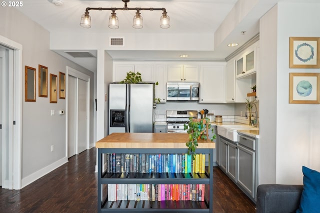 kitchen with stainless steel appliances, visible vents, dark wood-style floors, and a sink