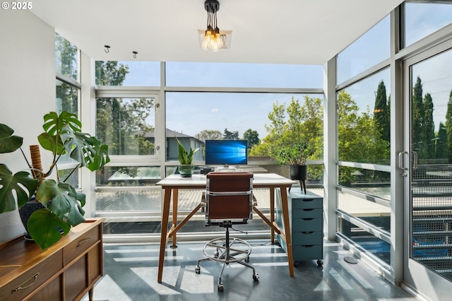 sunroom / solarium featuring concrete flooring, a wall of windows, and a healthy amount of sunlight