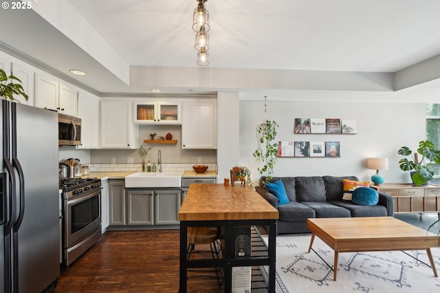kitchen with a sink, stainless steel appliances, recessed lighting, white cabinetry, and dark wood-type flooring
