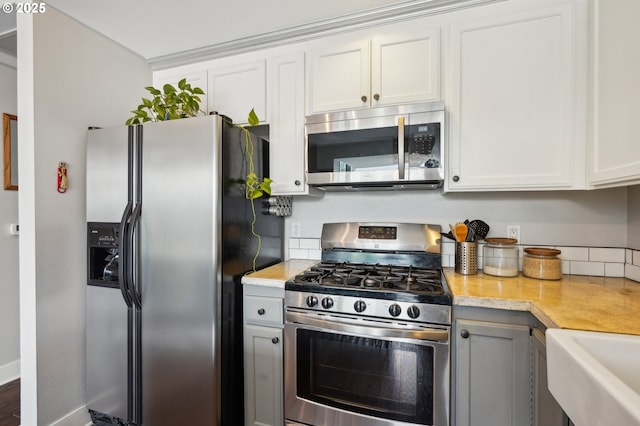 kitchen with white cabinets, stainless steel appliances, baseboards, and a sink