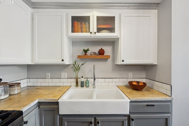 kitchen featuring light countertops, a sink, gray cabinets, and range with gas cooktop