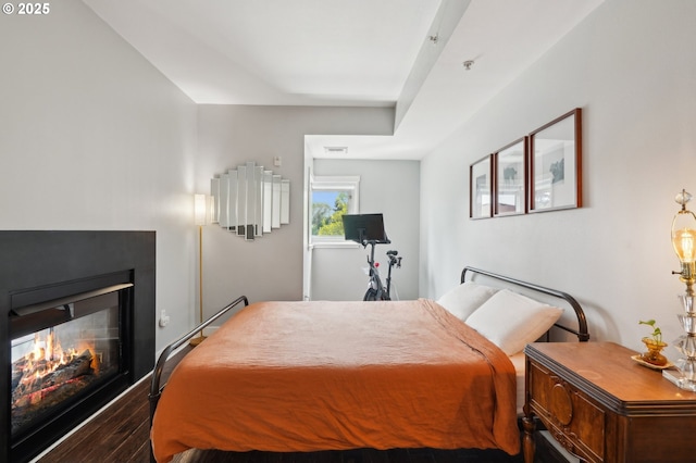 bedroom featuring visible vents, a multi sided fireplace, and wood finished floors