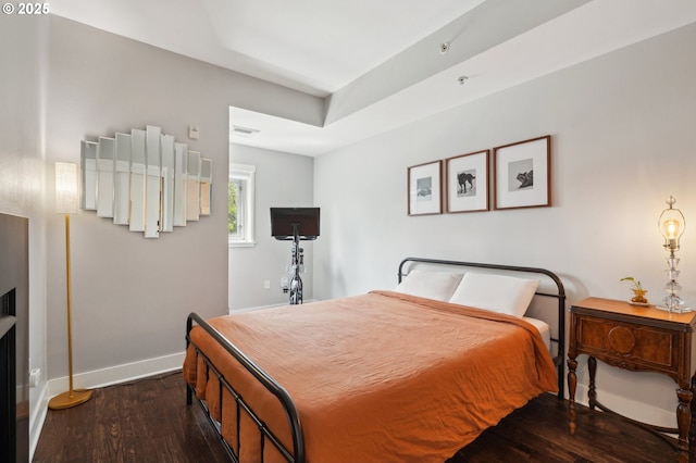 bedroom with baseboards, wood finished floors, and visible vents