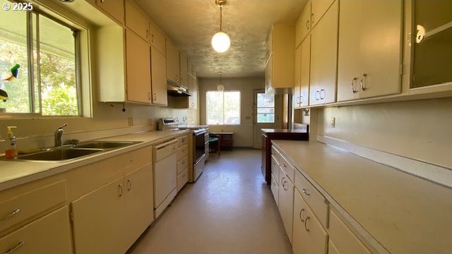 kitchen with light countertops, a sink, white dishwasher, and stainless steel electric range oven