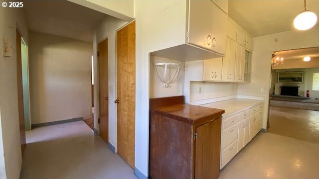 kitchen featuring finished concrete flooring, hanging light fixtures, and white cabinets