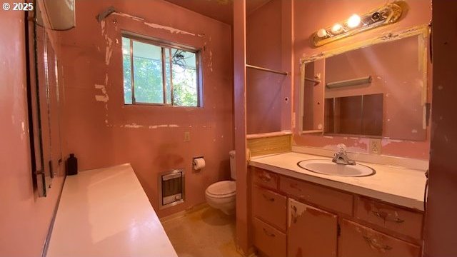bathroom with heating unit, vanity, and toilet