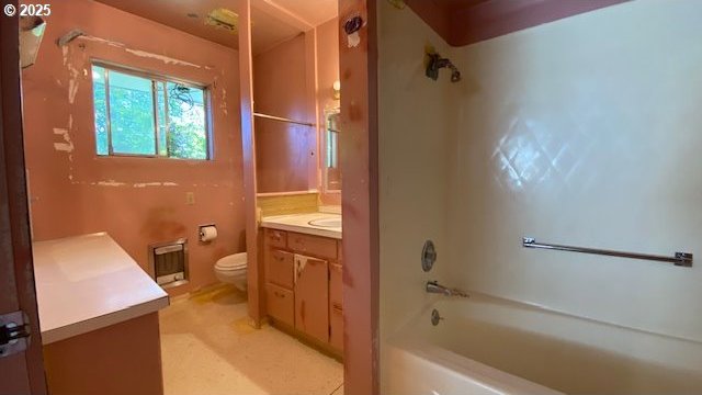 bathroom with toilet, heating unit, shower / bathing tub combination, and vanity