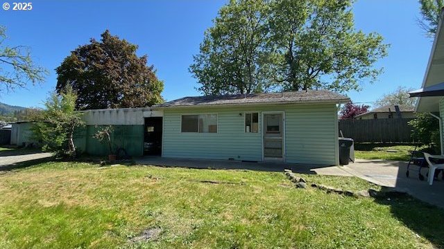 back of property featuring a lawn, fence, and a patio area