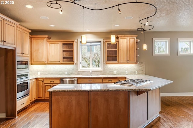 kitchen with backsplash, open shelves, light wood-style floors, stainless steel appliances, and a sink