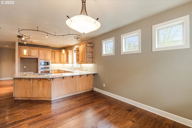 kitchen featuring baseboards, open shelves, a peninsula, a sink, and stainless steel appliances