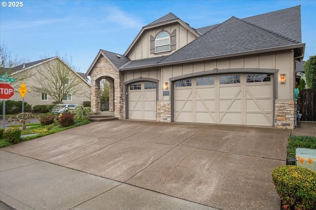 view of front of property with stone siding, driveway, roof with shingles, and board and batten siding