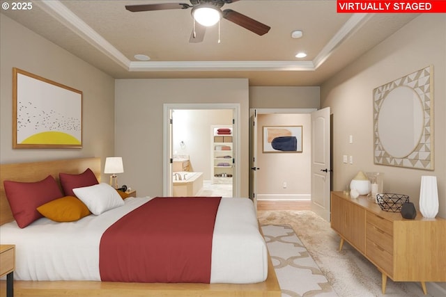 bedroom with a tray ceiling, recessed lighting, ensuite bathroom, and ornamental molding