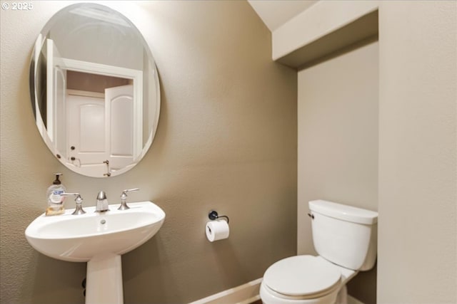 half bathroom featuring baseboards and toilet