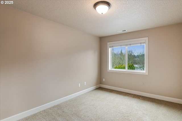 empty room with carpet, baseboards, visible vents, and a textured ceiling